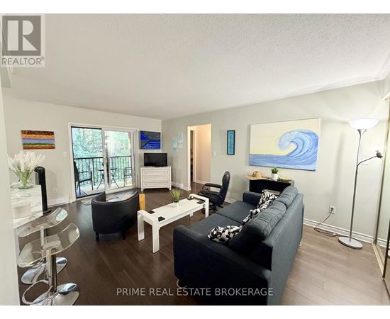 A living room with a black couch, a white coffee table, and a painting on the wall.