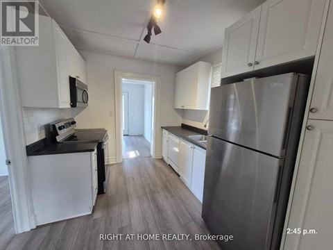 A kitchen with white cabinets and a stainless steel refrigerator.