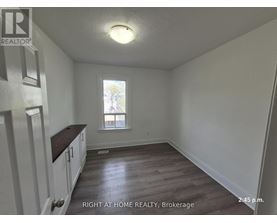 A room with wooden floors and white walls, with a window and a door on the left side.