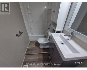 A bathroom with a toilet, sink, and mirror.