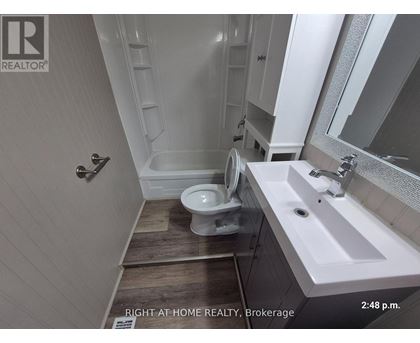 A bathroom with a toilet, sink, and mirror.