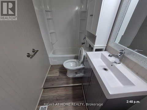 A bathroom with a toilet, sink, and mirror.