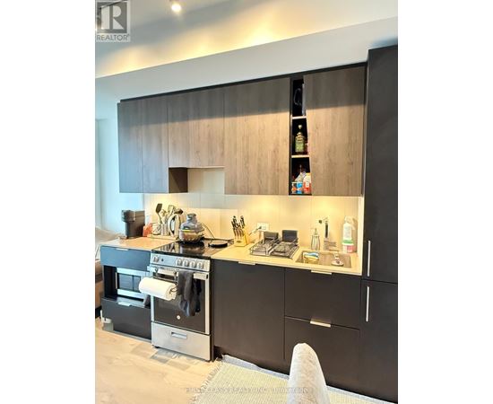 A modern kitchen with black cabinets and a stove top oven.