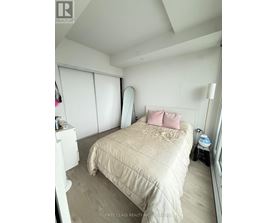 A bedroom with a bed, a nightstand, and a window with blinds.