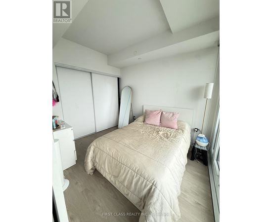 A bedroom with a bed, a nightstand, and a window with blinds.