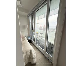 A bedroom with a large window overlooking a cityscape.