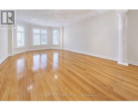 A spacious room with wooden flooring and white walls.