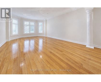 A spacious room with wooden flooring and white walls.