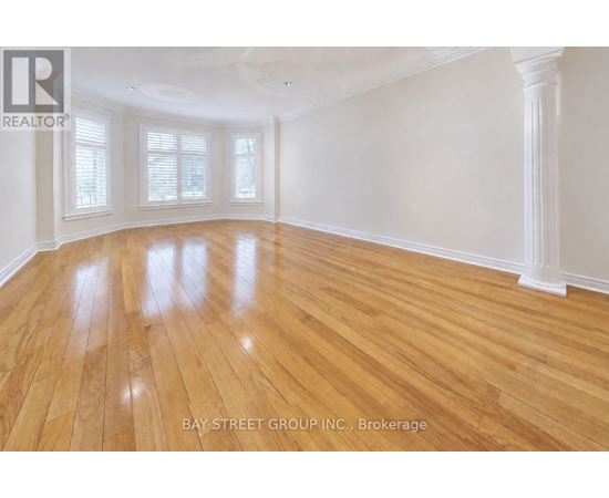 A spacious room with wooden flooring and white walls.