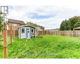 A small white shed with a blue door is situated in a grassy backyard.