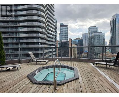 A rooftop with a hot tub and chairs overlooking a city skyline.