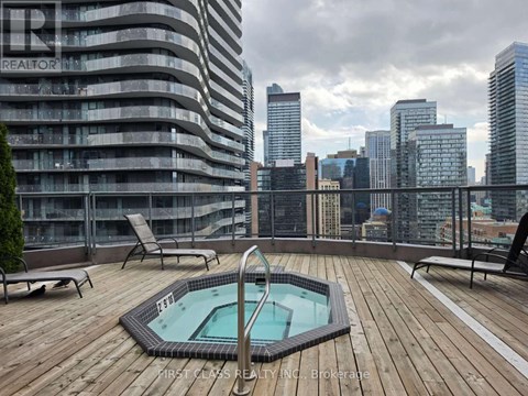 A rooftop with a hot tub and chairs overlooking a city skyline.