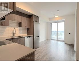 A well-lit kitchen with wooden cabinets and a stainless steel refrigerator.