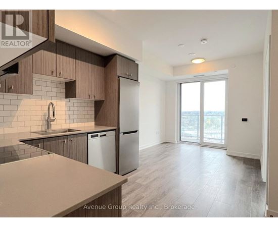 A well-lit kitchen with wooden cabinets and a stainless steel refrigerator.