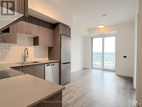 A well-lit kitchen with wooden cabinets and a stainless steel refrigerator.
