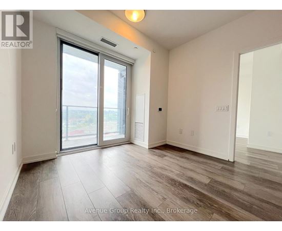 A spacious room with a sliding glass door leading to a balcony.