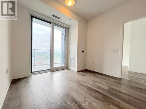 A spacious room with a sliding glass door leading to a balcony.