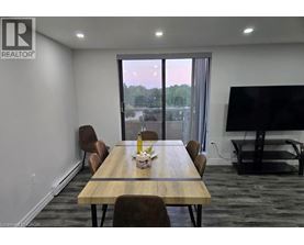 A conference room with a long table and chairs, a television, and a view of the outdoors through a large window.