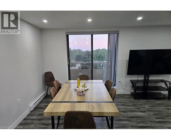 A conference room with a long table and chairs, a television, and a view of the outdoors through a large window.