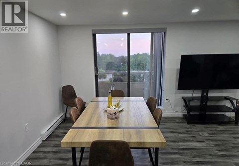 A conference room with a long table and chairs, a television, and a view of the outdoors through a large window.