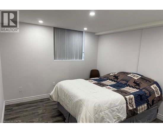 A bedroom with a bed, chair, and window.