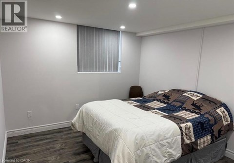 A bedroom with a bed, chair, and window.