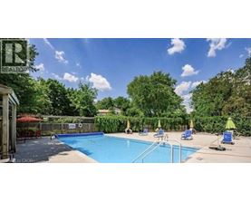A pool surrounded by trees and a fence with a sign that says "REALTOR".