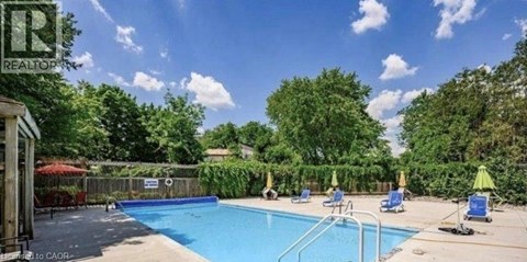 A pool surrounded by trees and a fence with a sign that says "REALTOR".