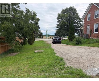 A car is parked on a gravel driveway in front of a house.