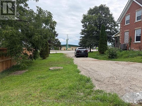 A car is parked on a gravel driveway in front of a house.