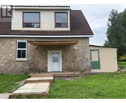 A stone house with a white door and a green door on the side.