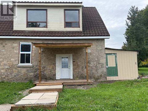 A stone house with a white door and a green door on the side.