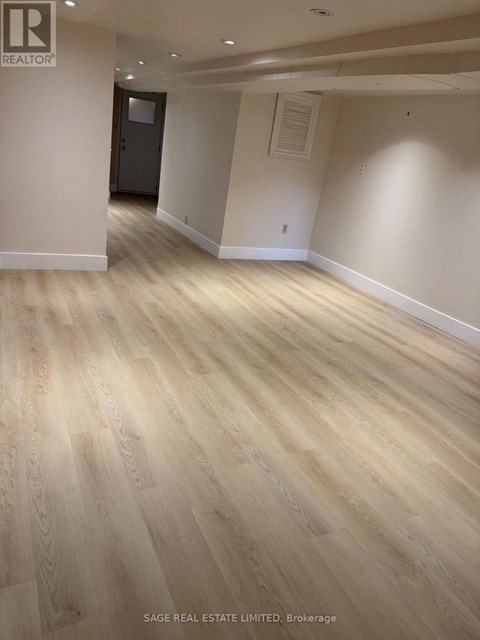 A room with wooden flooring and a door in the background.