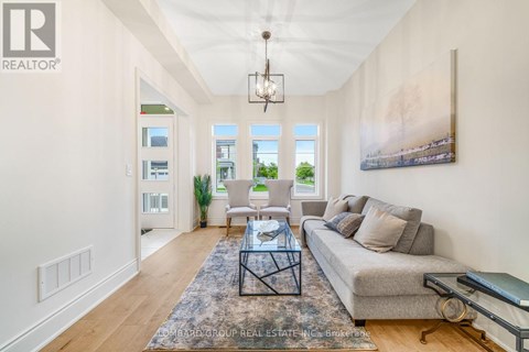 A well-lit living room with a grey sofa and a glass coffee table.