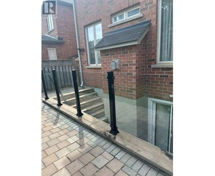 A brick house with a black railing and a glass door.