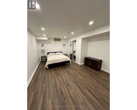 A bedroom with a bed, nightstand, and a wooden floor.