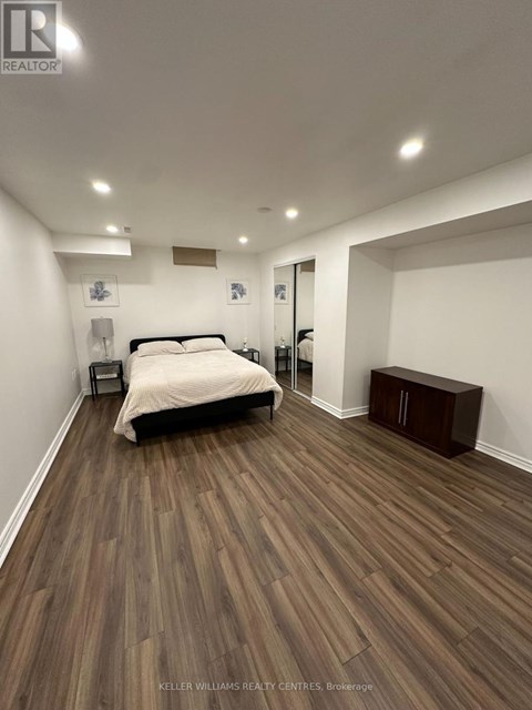 A bedroom with a bed, nightstand, and a wooden floor.