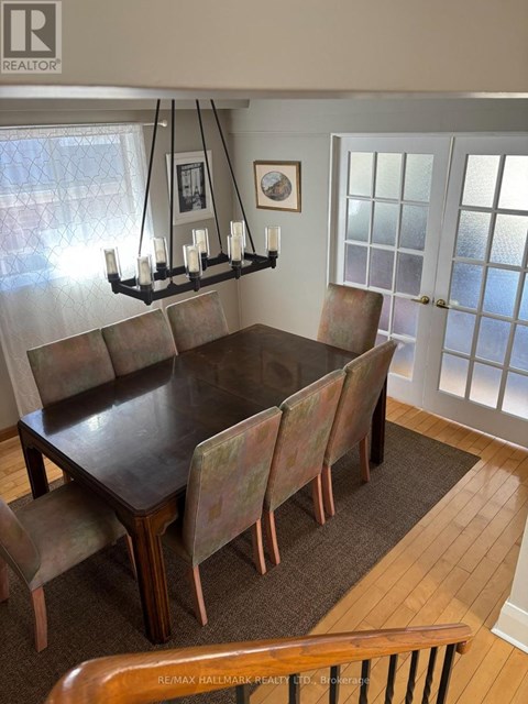 A brown dining table with chairs and a chandelier in a room.