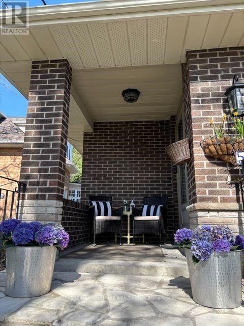 A patio with two chairs and a table with a basket of flowers on it.