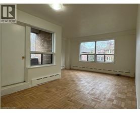 A room with a wooden floor and a window overlooking a cityscape.