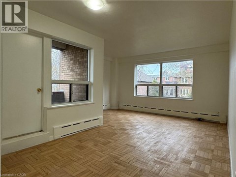A room with a wooden floor and a window overlooking a cityscape.