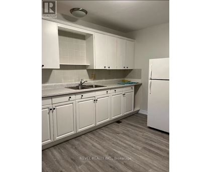 A kitchen with white cabinets and a white refrigerator.