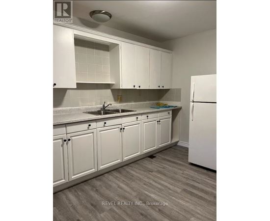 A kitchen with white cabinets and a white refrigerator.