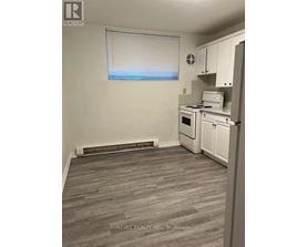 A kitchen with white appliances and a window with blinds.