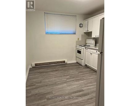 A kitchen with white appliances and a window with blinds.