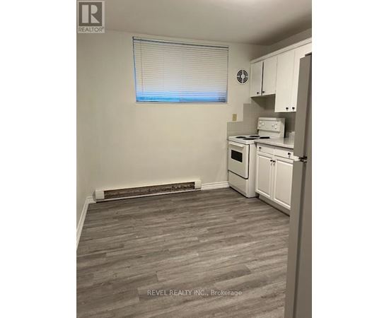 A kitchen with white appliances and a window with blinds.