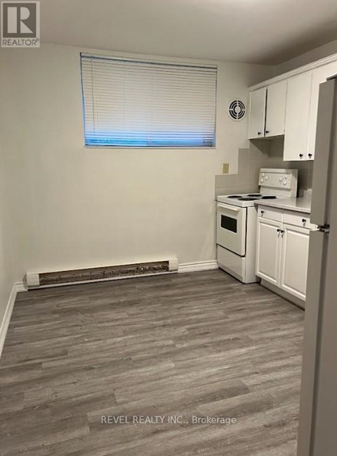 A kitchen with white appliances and a window with blinds.