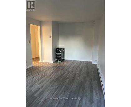 A room with a wooden floor and a white wall with a door.