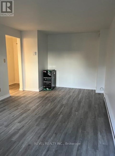 A room with a wooden floor and a white wall with a door.