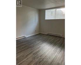 A room with a window and a wooden floor.